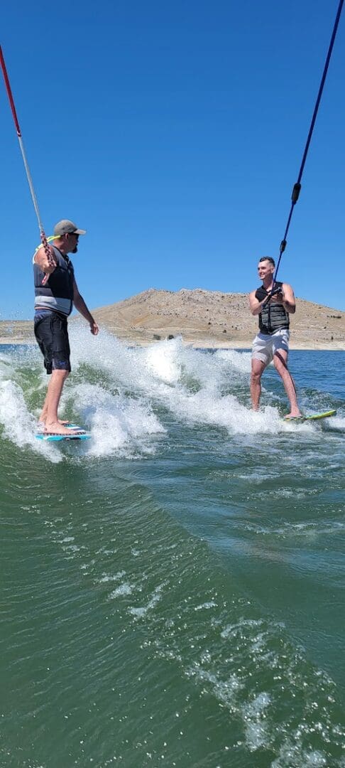 Two men are on water skis in the ocean.